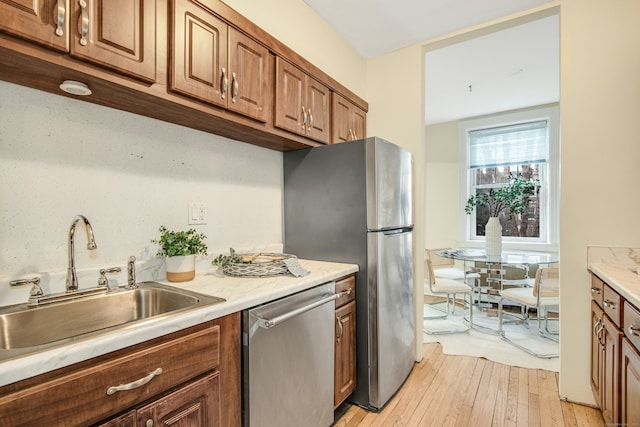 kitchen featuring sink, dishwasher, and light wood-type flooring