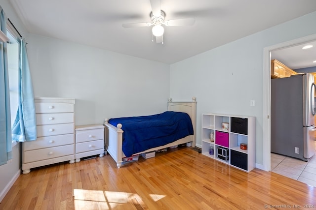 bedroom with hardwood / wood-style flooring, stainless steel refrigerator, and ceiling fan