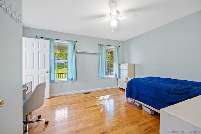 bedroom with hardwood / wood-style floors, ceiling fan, and multiple windows