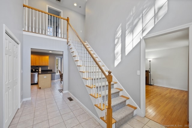 stairway with hardwood / wood-style flooring and a towering ceiling