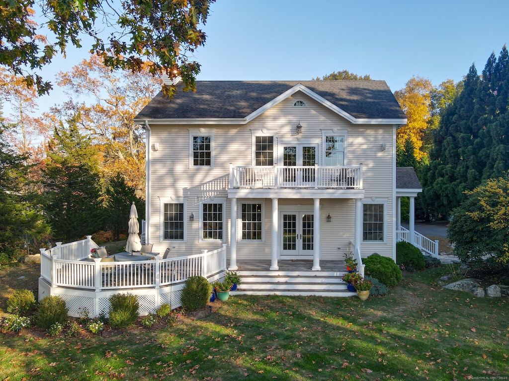 back of property with a yard, french doors, and a wooden deck