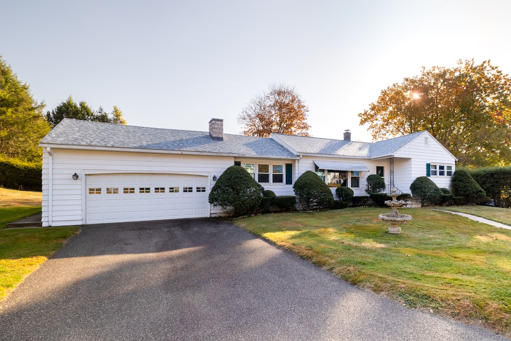 single story home featuring a garage and a front lawn