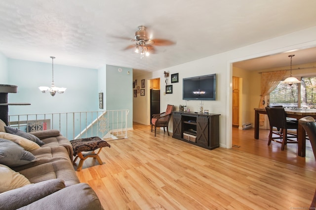 living room with hardwood / wood-style floors, a baseboard heating unit, and ceiling fan with notable chandelier