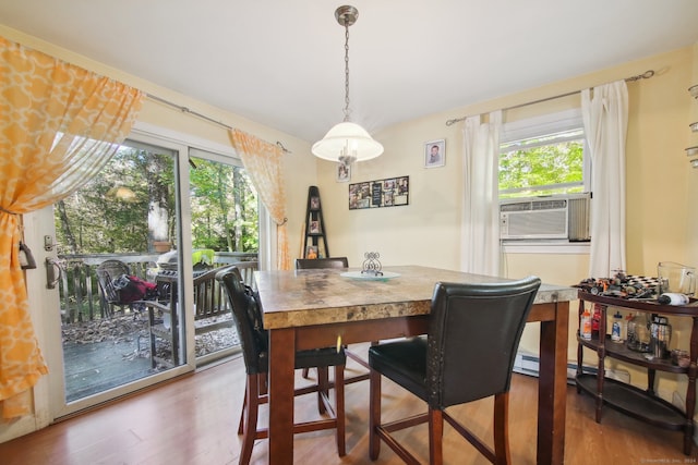 dining space with cooling unit, a healthy amount of sunlight, and hardwood / wood-style flooring