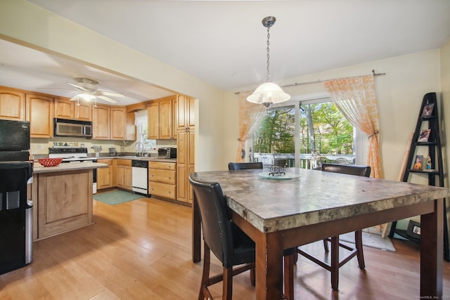 dining area with sink, light wood-type flooring, and ceiling fan