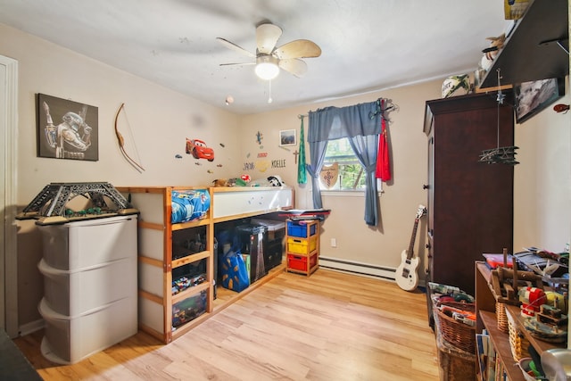 bedroom with hardwood / wood-style floors, baseboard heating, and ceiling fan