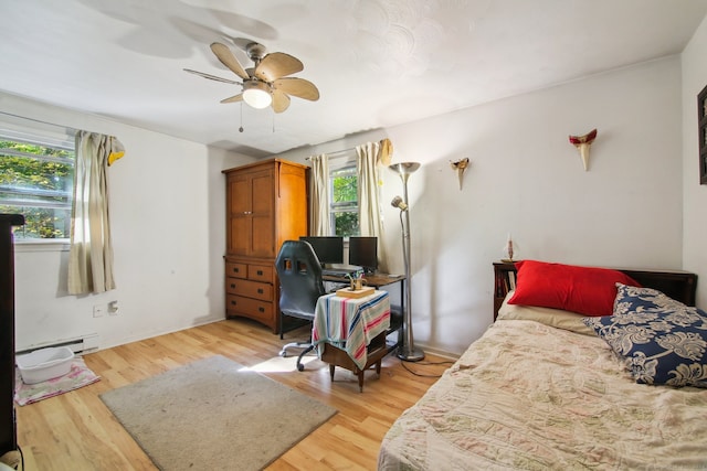 bedroom with light hardwood / wood-style flooring, a baseboard heating unit, and ceiling fan