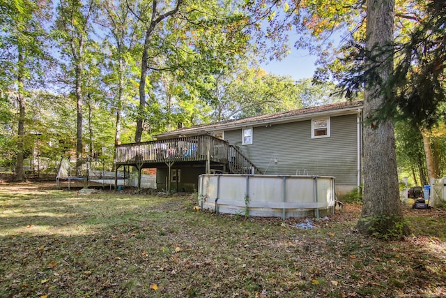 back of property featuring a yard, a trampoline, and a pool side deck