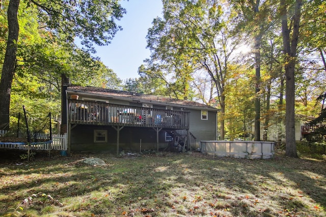 rear view of property with a lawn, a trampoline, and a swimming pool side deck