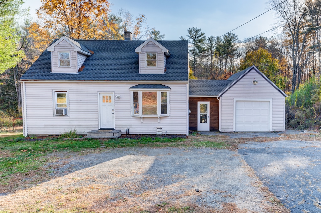 new england style home with cooling unit and a garage