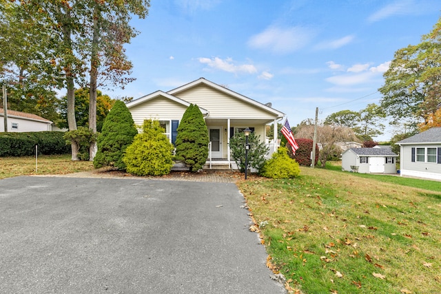 view of front of home featuring a storage shed, a front yard, and covered porch