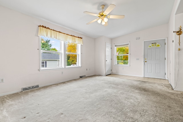 unfurnished room featuring ceiling fan, a wealth of natural light, and light colored carpet