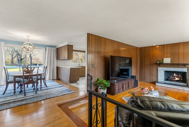 living room featuring light hardwood / wood-style floors, wood walls, a chandelier, and a fireplace