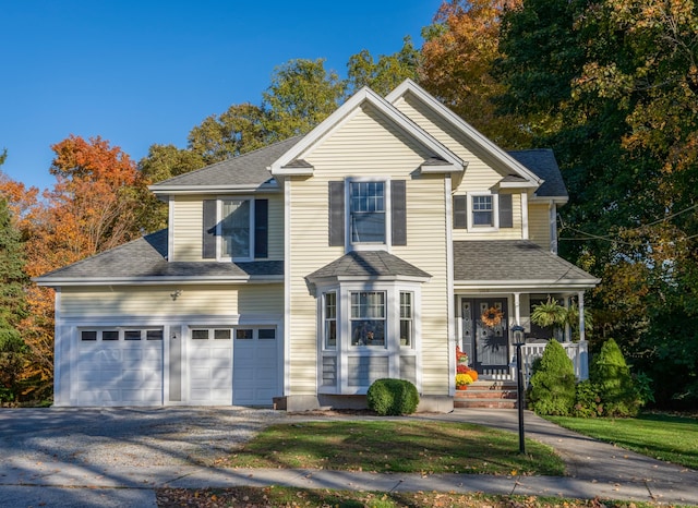 view of property with covered porch and a garage