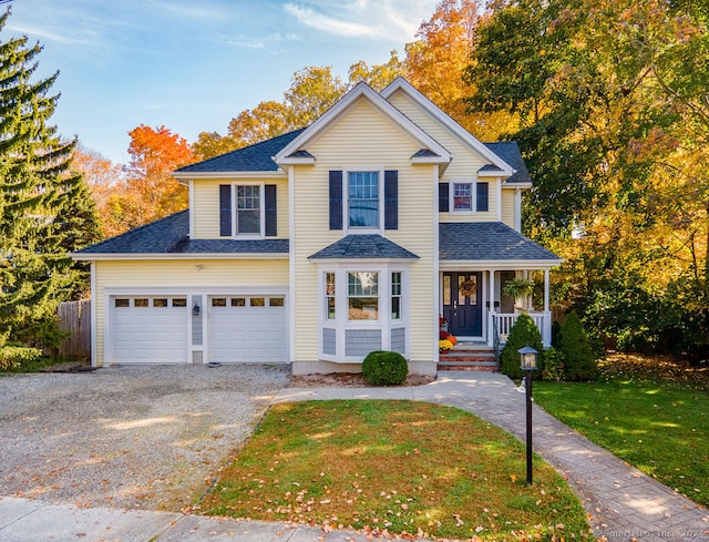 front facade with covered porch, a front yard, and a garage