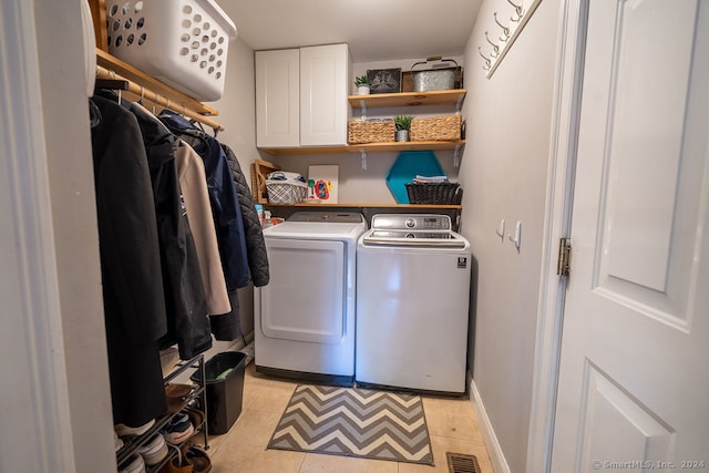 laundry room with light tile patterned flooring, washing machine and dryer, and cabinets