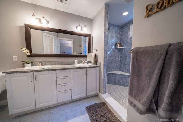 bathroom with vanity, a tile shower, and tile patterned floors