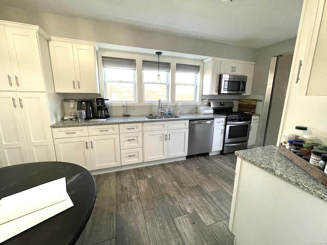 kitchen with sink, white cabinetry, stainless steel appliances, and hanging light fixtures