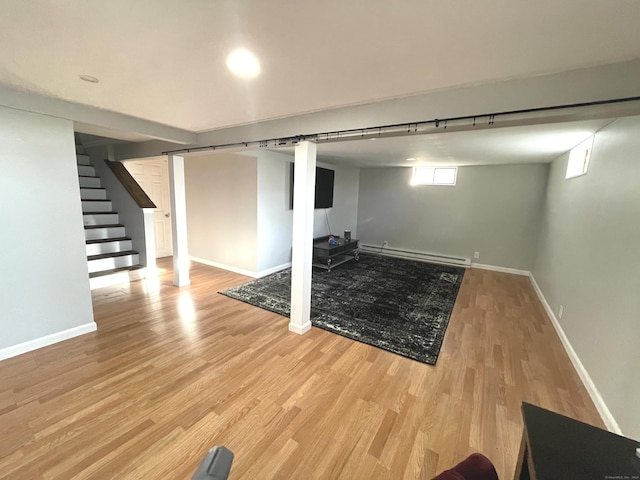 basement featuring light wood-type flooring and baseboard heating