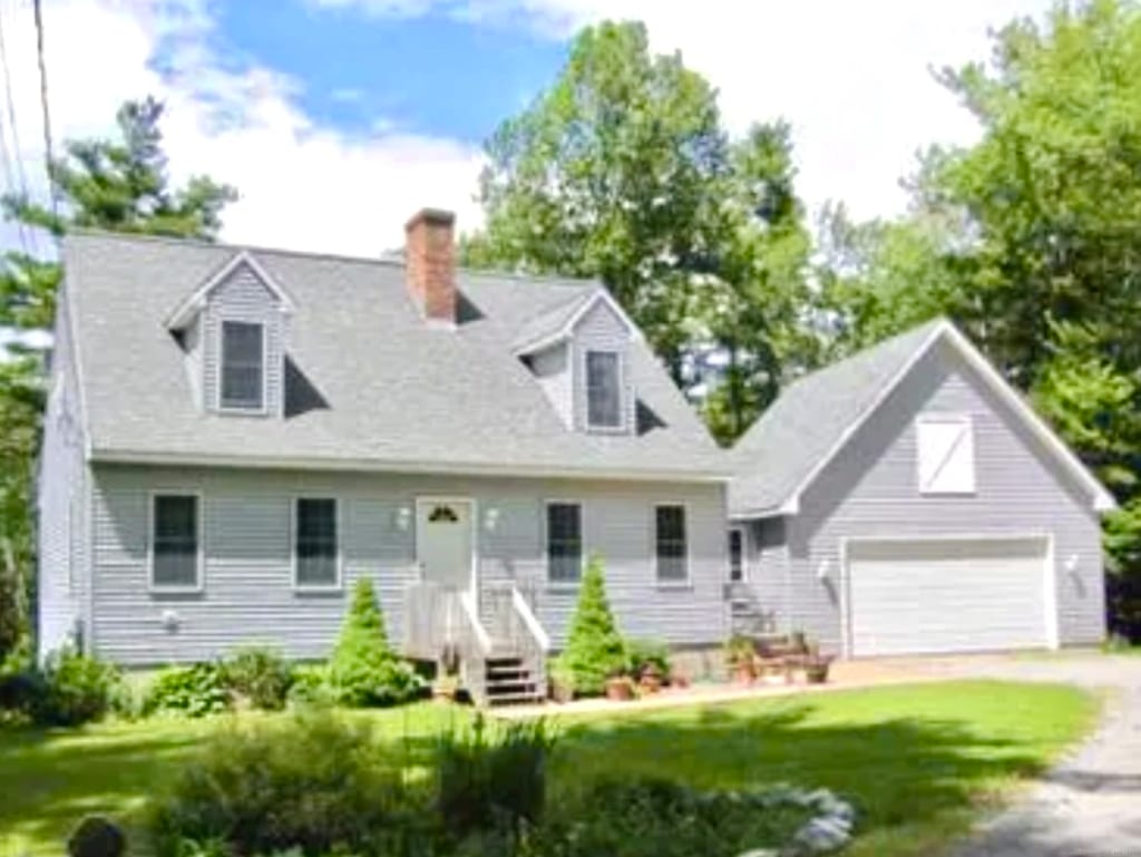 new england style home featuring a front yard and a garage