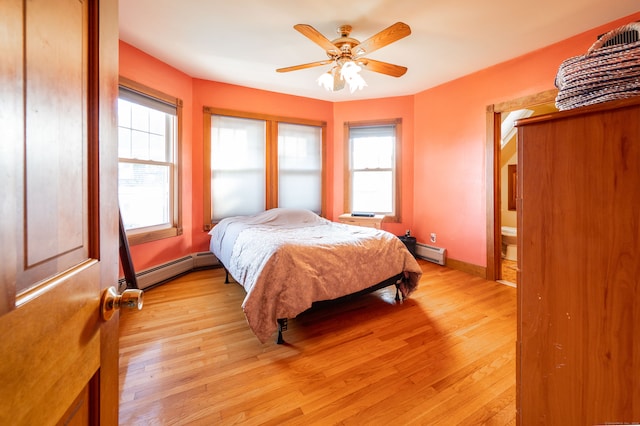 bedroom with light hardwood / wood-style flooring, a baseboard heating unit, and ceiling fan