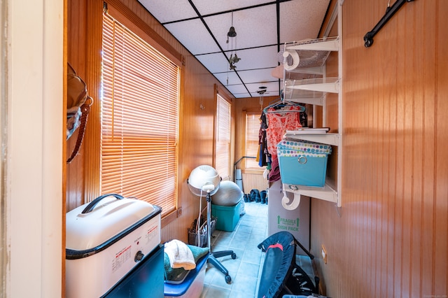 interior space featuring wooden walls, a paneled ceiling, and a healthy amount of sunlight