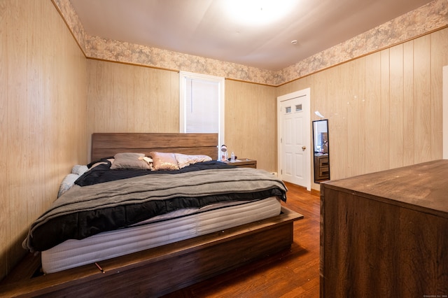 bedroom with wooden walls and dark wood-type flooring