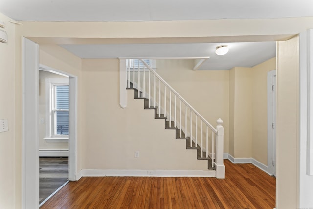 stairs featuring wood-type flooring and a baseboard radiator