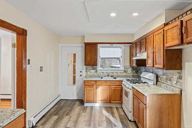 kitchen with decorative backsplash, white gas range oven, a baseboard radiator, and sink