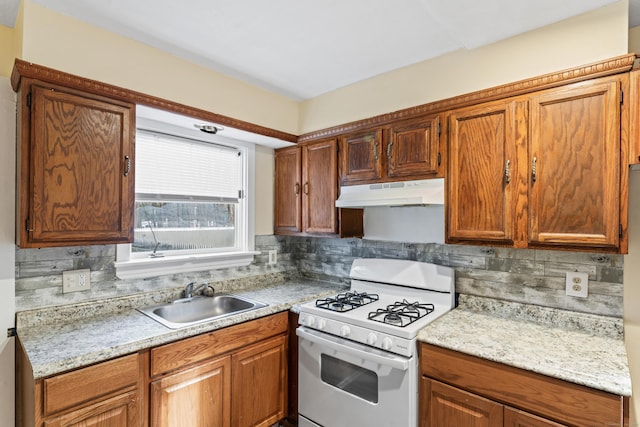 kitchen with tasteful backsplash, light stone countertops, white gas stove, and sink