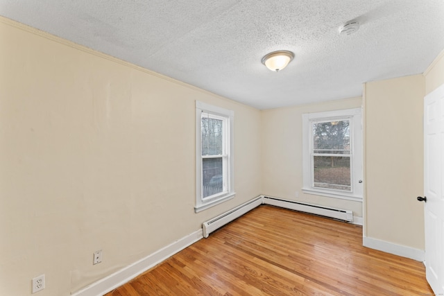 empty room with light hardwood / wood-style floors, a textured ceiling, and a baseboard heating unit