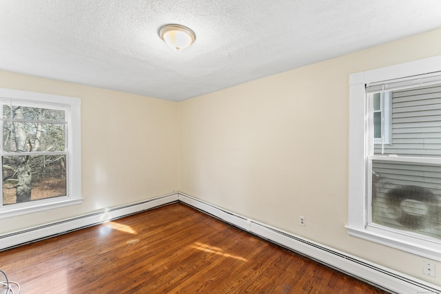 spare room with baseboard heating, hardwood / wood-style floors, and a textured ceiling