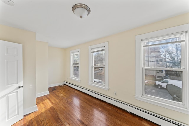 unfurnished room featuring hardwood / wood-style floors and baseboard heating