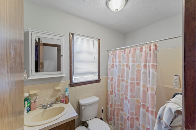 bathroom with a textured ceiling, toilet, tile walls, a shower with curtain, and vanity