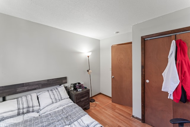 bedroom featuring light hardwood / wood-style flooring, a textured ceiling, and a closet