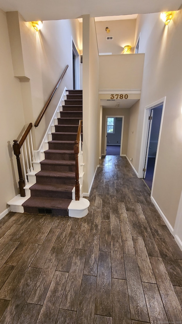 foyer entrance featuring a towering ceiling and dark wood-type flooring