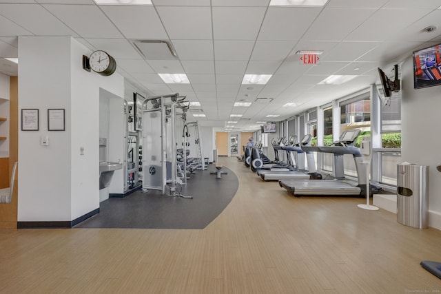 exercise room with a paneled ceiling and wood-type flooring