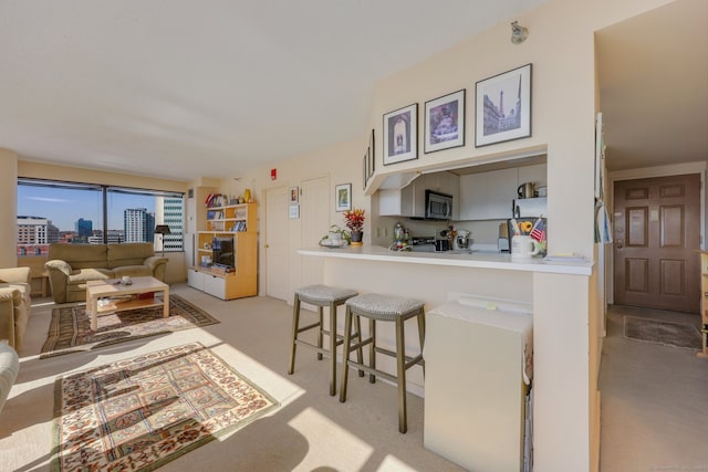 kitchen featuring light carpet, stainless steel appliances, a breakfast bar area, and kitchen peninsula