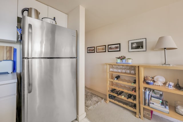 kitchen with light carpet, stainless steel fridge, and white cabinets