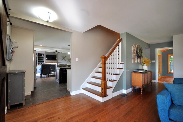 stairway with hardwood / wood-style floors and ceiling fan