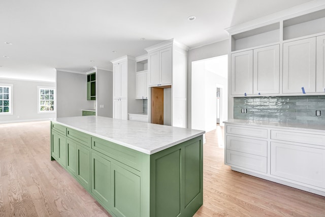 kitchen featuring green cabinetry, a kitchen island, white cabinetry, light hardwood / wood-style floors, and decorative backsplash