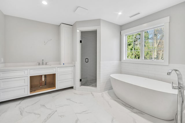 bathroom featuring vanity, shower with separate bathtub, and tile walls