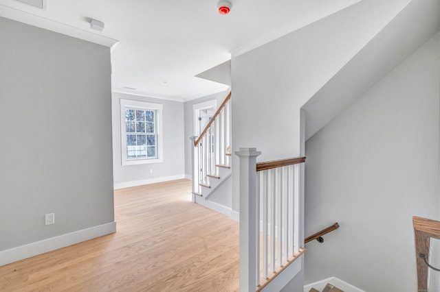 stairway with ornamental molding and hardwood / wood-style flooring