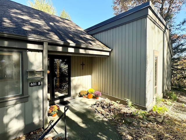 doorway to property featuring roof with shingles