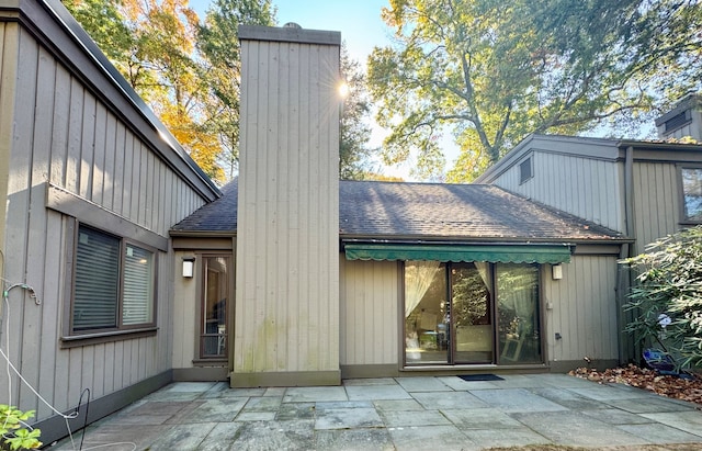 back of property featuring roof with shingles, a chimney, and a patio area