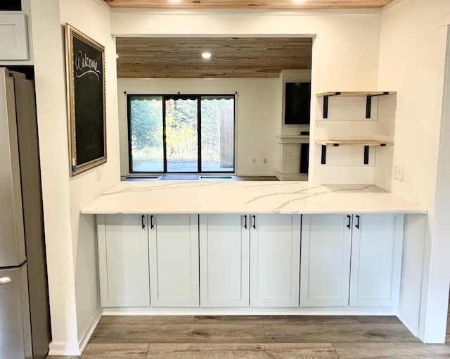 kitchen with wood ceiling, open shelves, light stone counters, freestanding refrigerator, and recessed lighting