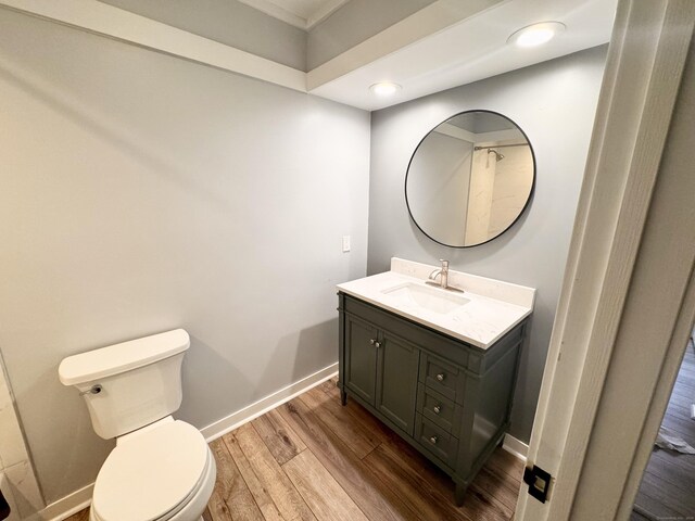 bathroom featuring wood finished floors, baseboards, vanity, toilet, and recessed lighting