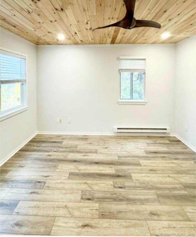 spare room featuring wood ceiling, ceiling fan, baseboard heating, wood finished floors, and baseboards