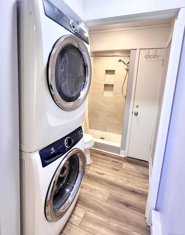 washroom with light wood-style floors, stacked washer and clothes dryer, and laundry area
