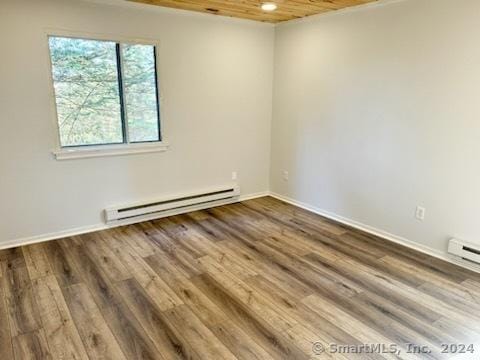 unfurnished room with baseboards, a baseboard radiator, and wood finished floors
